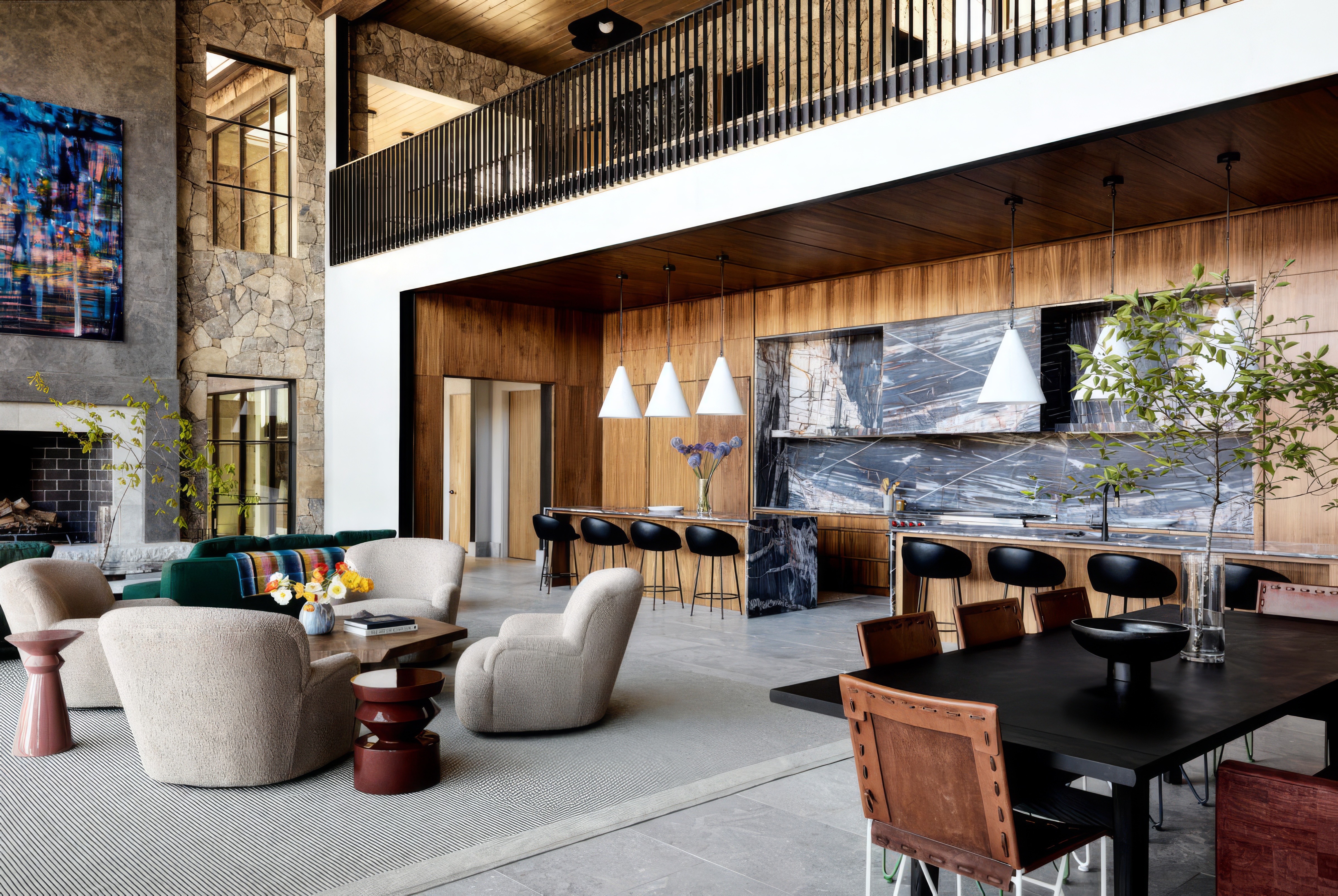 Open great room with stone fireplace, loft balcony, marble kitchen wall and modern furnishings
